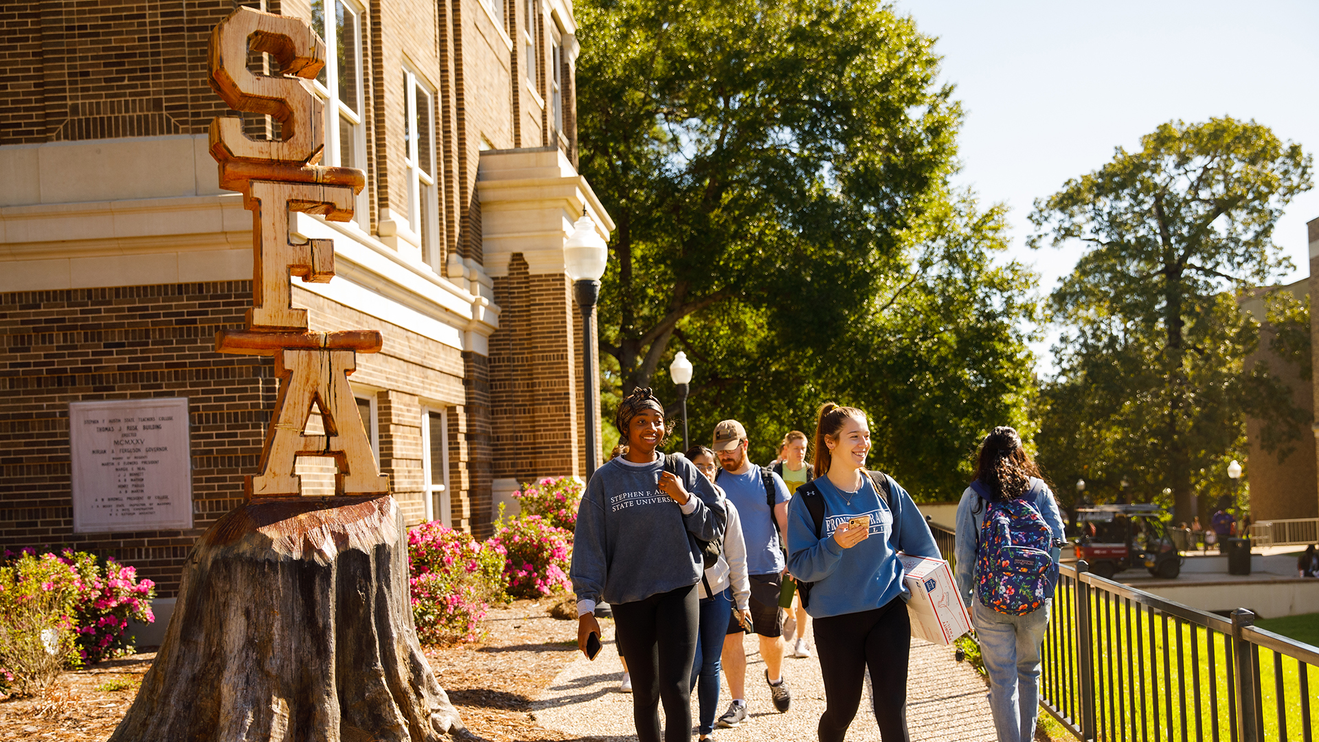 Wooden carving of SFA letters with students walking past